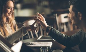 Persona entregando smartphone amigablemente en cafetería, generando conexión y comunicación. Ambiente cálido y acogedor, ideal para socialización.