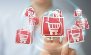 Carritos de compra rojos flotan; mano los toca en un espacio futurista digital. Ventas digitales y comercio electrónico en sinergia.