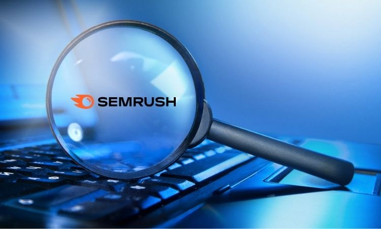 Lupa enfocando el logo de SEMrush sobre un teclado, simbolizando análisis y herramientas de marketing digital.