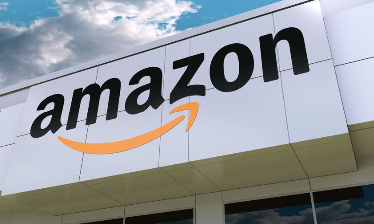 Edificio muestra logo "amazon" en letras negras. Acción: Promociona presencia de marca. Contexto: Exterior, cielo nublado. Palabras clave: comercio, visibilidad.
