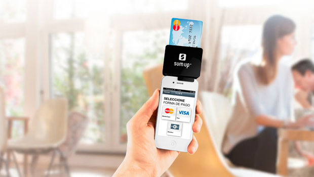 Teléfono con lector SumUp procesa pago con tarjeta en sala luminosa. Texto: "SELECCIONE FORMA DE PAGO, MasterCard, VISA". Innovación fintech.
