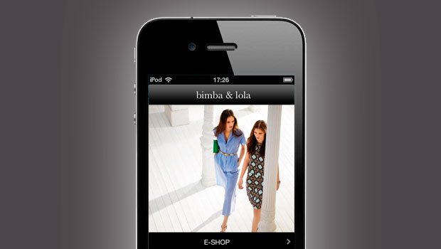 Teléfono muestra en pantalla tienda online "bimba & lola". Dos mujeres caminan, vestidas de moda. Fondo blanco. Texto destaca "E-SHOP". Innovación retail.