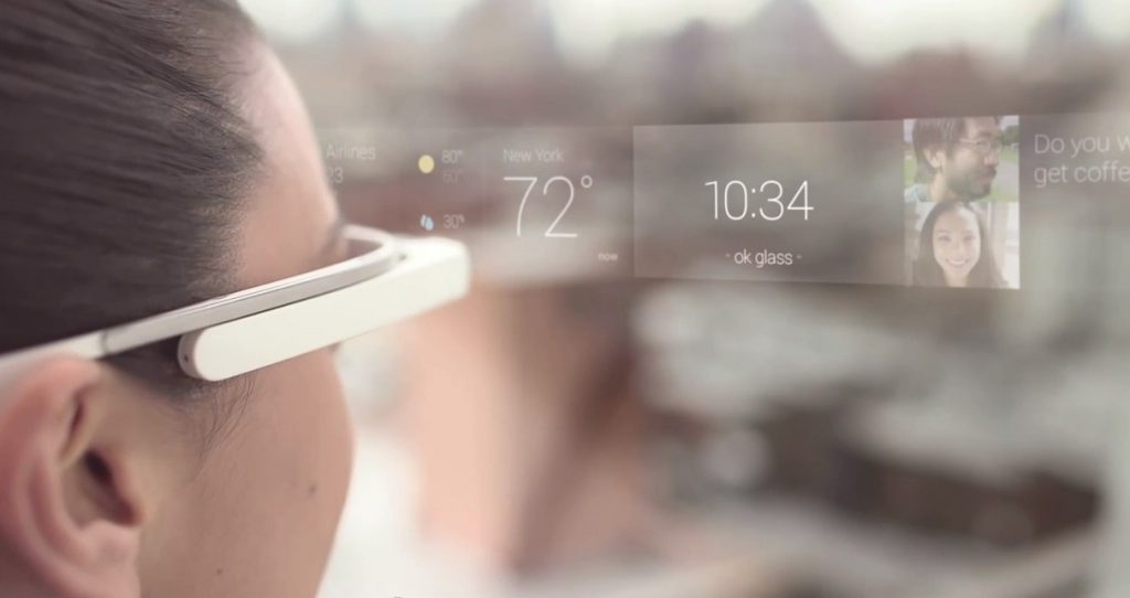 Gafas inteligentes proyectan información: clima "72°F", hora "10:34", mensaje. Persona las lleva puestas, ciudad al fondo. Tecnología innovadora.