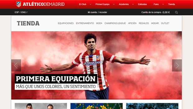Jugador de fútbol posando con brazos abiertos, vistiendo la camiseta del Atlético de Madrid. Texto: "PRIMERA EQUIPACIÓN: MÁS QUE UNOS COLORES, UN SENTIMIENTO". Página web del club.