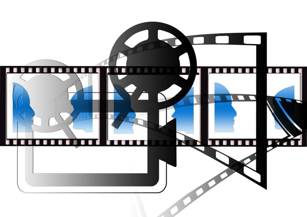 Carrete de película con siluetas de caras azules proyectándose, mostrando creatividad en un ambiente de cine y medios visuales.