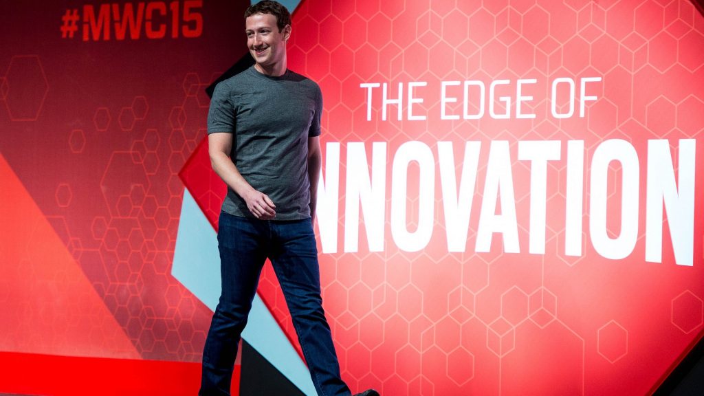 Una persona camina frente a un fondo rojo con el texto: "#MWC15" y "THE EDGE OF INNOVATION" en letras blancas. Contexto de innovación tecnológica.