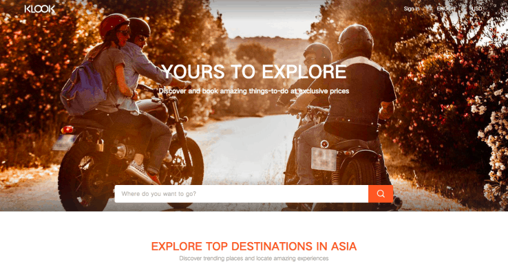 Motoristas circulan por un camino rodeado de árboles con hojas otoñales. Texto: "YOURS TO EXPLORE" y "EXPLORE TOP DESTINATIONS IN ASIA". Ideal para marketing de aventuras y viajes.