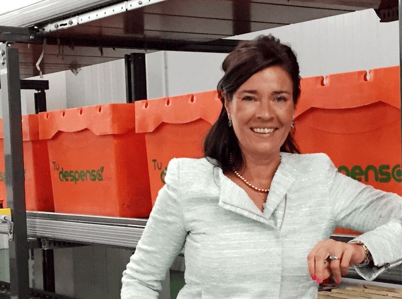 Persona sonriendo, apoyada en estantes con cajas naranjas de fondo. Texto: "Tu despensa". Ambiente de almacén. Contexto: logística y retail.
