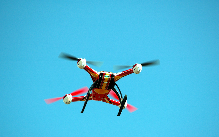 Un dron colorido vuela en el cielo azul claro, simbolizando innovación tecnológica y estrategias de marketing visual aéreo.