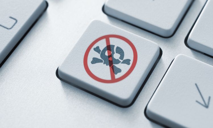 Tecla muestra un símbolo de calavera y huesos cruzados tachado. Contexto: teclado blanco. Concepto: protección digital, seguridad informática.