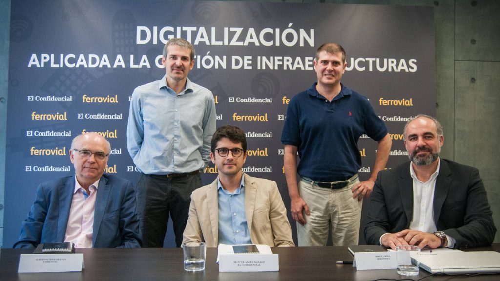 Cinco hombres posan en grupo, en un evento de digitalización para infraestructuras. Fondos muestran logos de "El Confidencial" y "Ferrovial". Carteles indican nombres: Alberto López, Manuel Ángel Méndez, Miguel Roda.