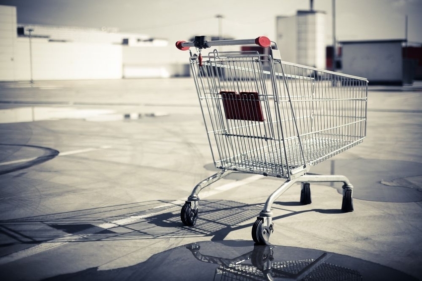 Carrito de compras metálico, inmóvil, en un aparcamiento vacío y soleado. Ideal para ilustrar conceptos de compras y consumo.