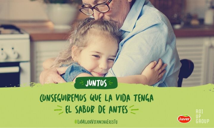 Niña abrazando a un adulto en una cocina hogareña. Texto: "JUNTOS CONSEGUIREMOS QUE LA VIDA TENGA EL SABOR DE ANTES #LaMejorVitaminaEresTú". Marketing emocional.