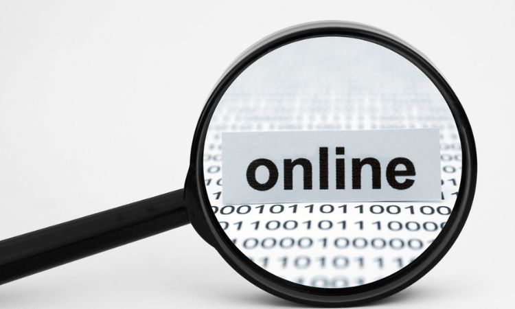 Lupa enfocando texto "online" sobre fondo de números binarios. Contexto digital, simboliza investigación y marketing en línea.