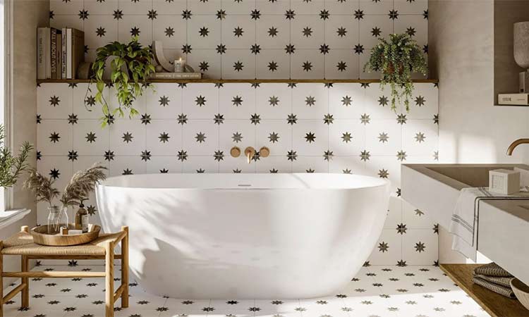 Bañera blanca independiente, situada en un baño con azulejos blancos decorados con estrellas negras. Alrededor, plantas, libros y luz natural.