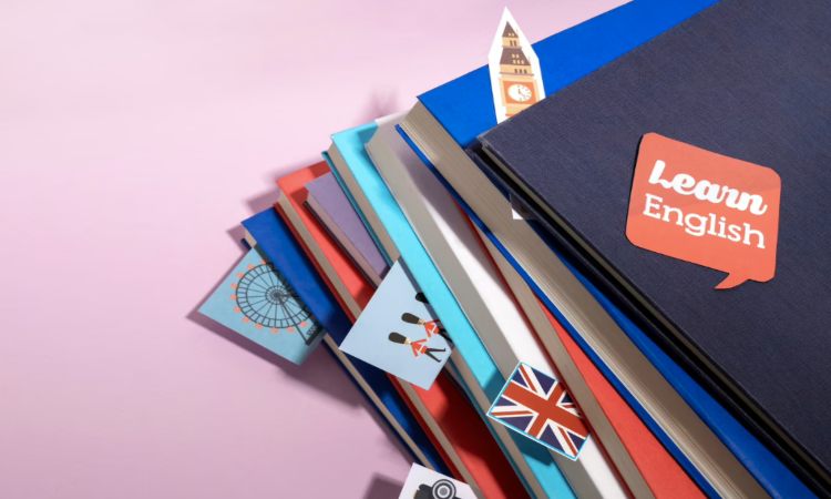 Libros apilados inclinados, con iconos británicos y texto "Learn English" en una portada. Contexto educativo, aprendizaje de inglés.