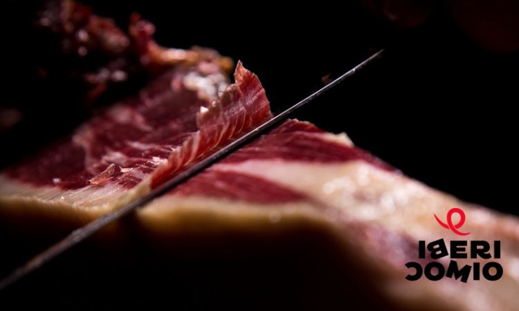 jamón siendo cortado, con el logo de ibericomio