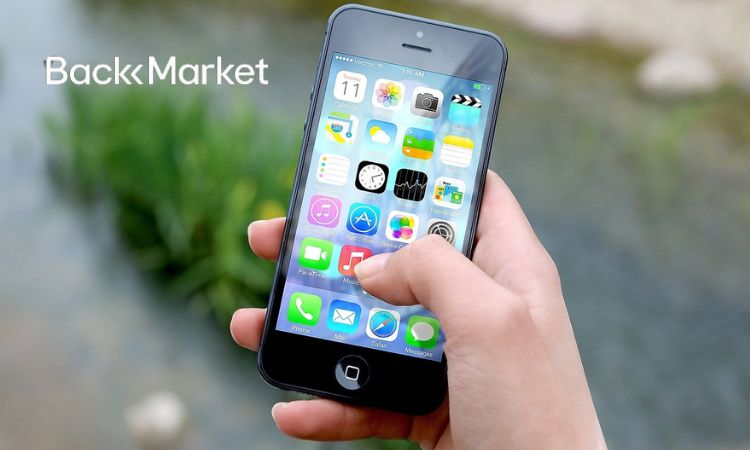 Un móvil en mano muestra aplicaciones coloridas. Fondo natural desenfocado. Texto: "Back Market". Ideal para marketing de productos reacondicionados.