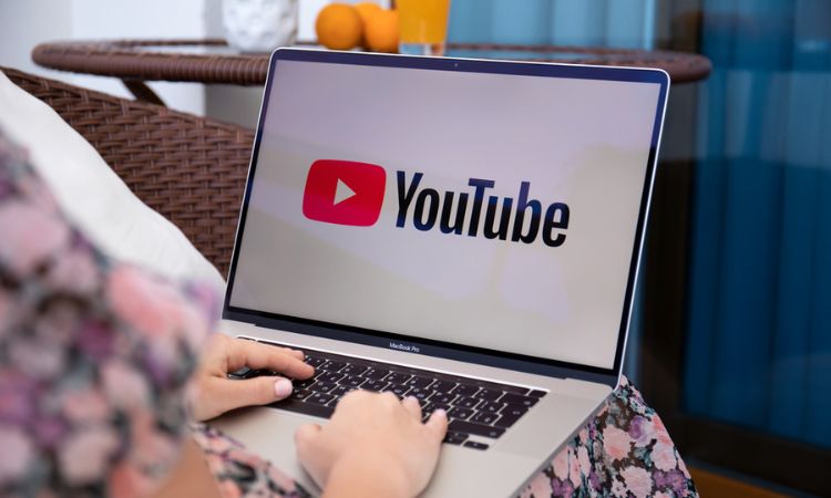 Fotografía de un ordenador portátil colocado sobre el regazo de una mujer que está usándolo para ver YouTube