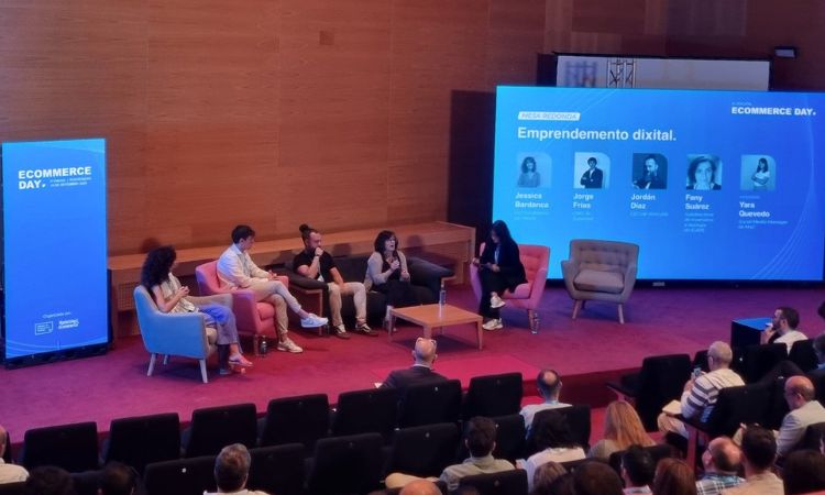 Panel de debate con cinco personas sentadas en sillones, hablando ante una audiencia. Carteles promocionales de fondo sobre "Ecommerce Day".