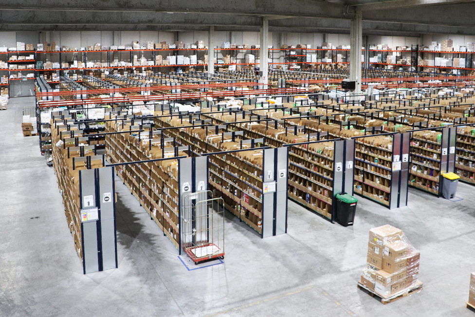 Estanter&iacute;as llenas de cajas organizadas en un amplio almac&eacute;n, mostrando eficiencia y gesti&oacute;n log&iacute;stica en un entorno de distribuci&oacute;n masiva.