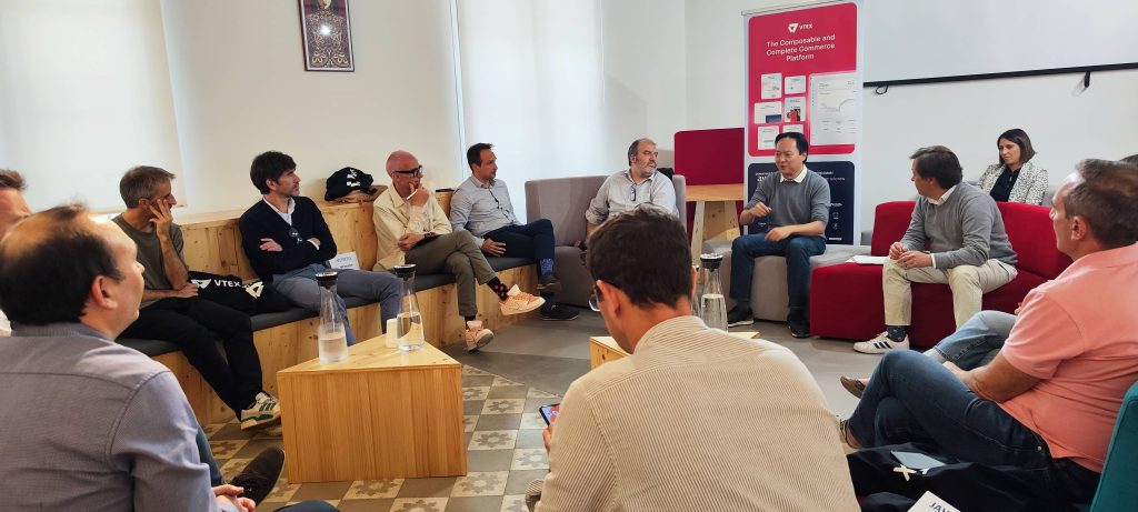Personas sentadas discuten en una sala de reuniones moderna, fondo con cartel "The Enterprise and Online Commerce Platform". Ambiente colaborativo y profesional.