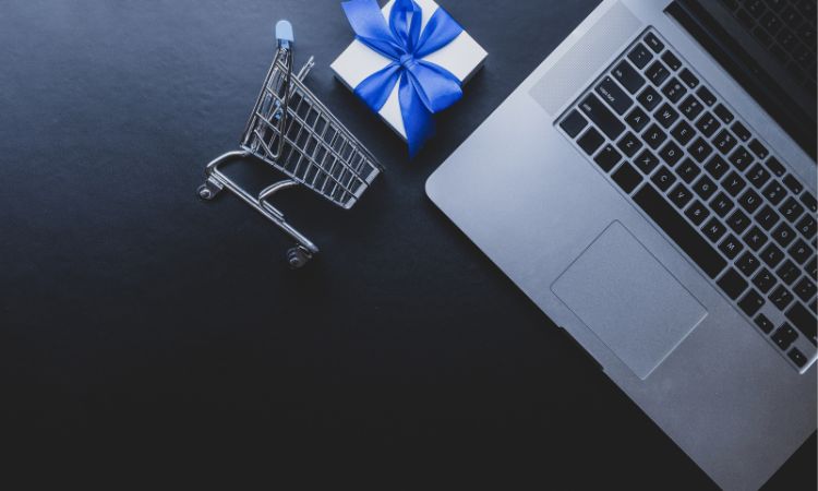 Imagen del teclado, un carrito de la compra pequeño y un pequeño regalo de color azul.