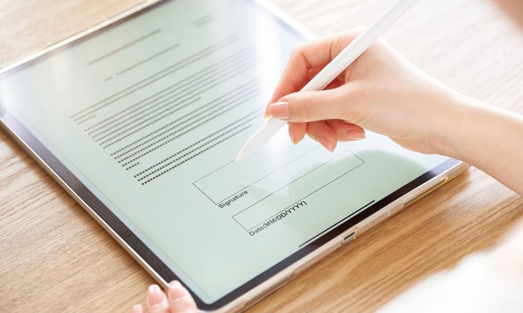 Una persona firmando un contrato en un ipad.